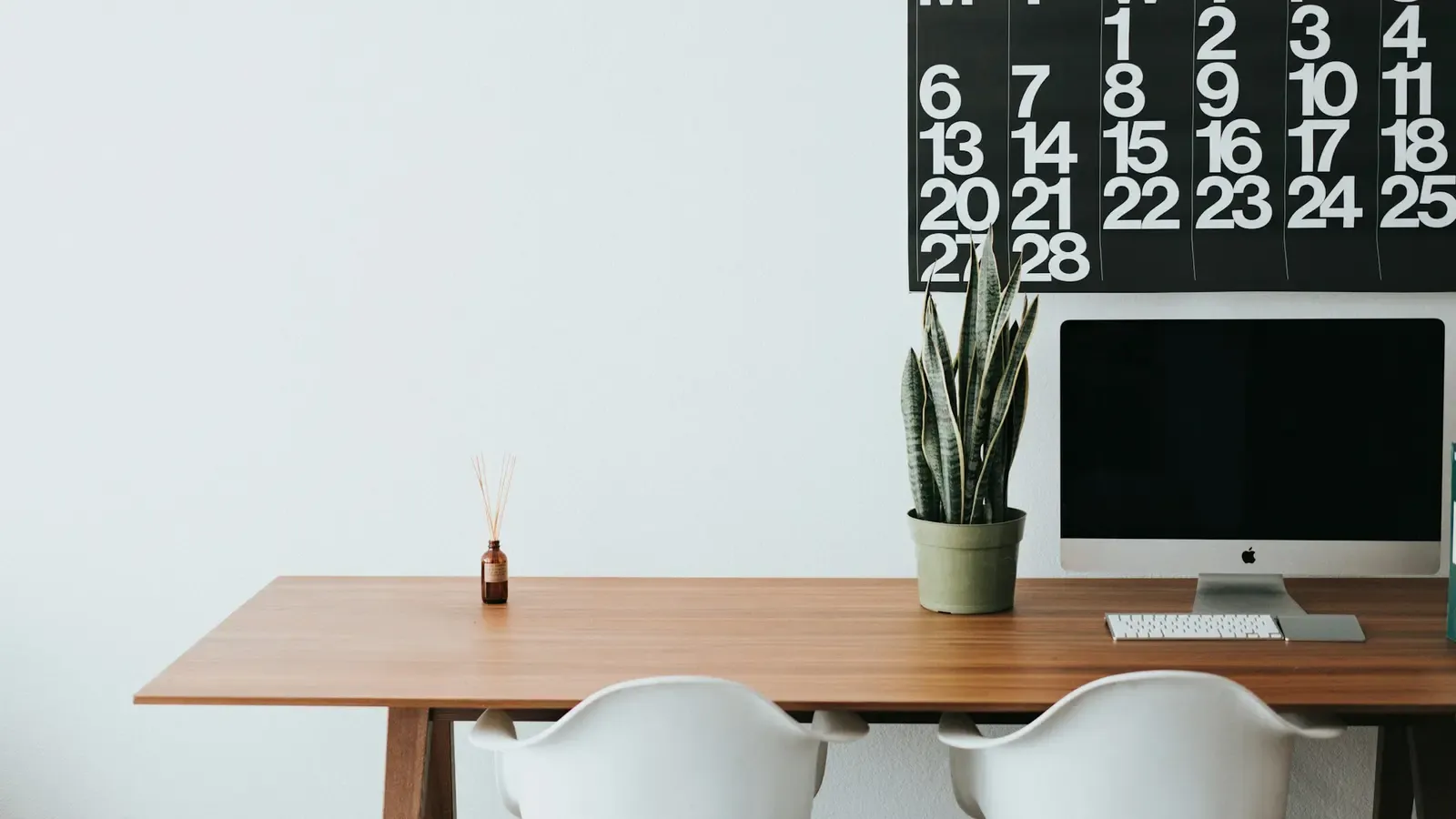 Escritório minimalista com mesa clara, cadeira e luz natural ampla.